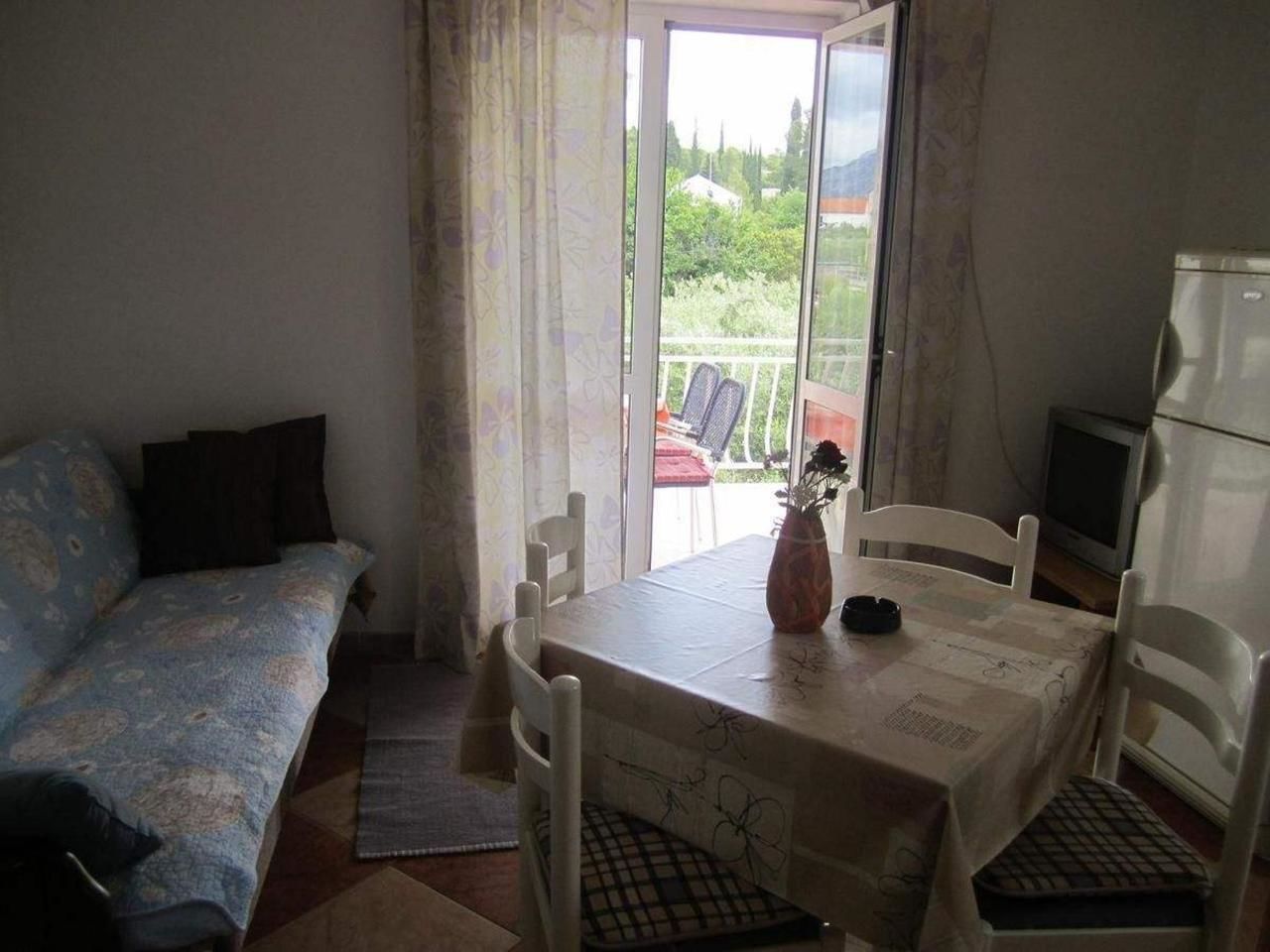 A small room with a sofa, a dining table with chairs, a TV, and a view of the outdoors.