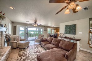 A spacious living room with a brown leather sofa, a patterned rug, and a ceiling fan. - CL 1105B Tranquility by the Shore (Canyon Lake)
