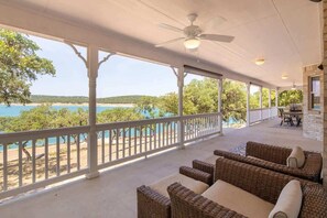 A covered outdoor area with wicker furniture, a ceiling fan, and a view of a beach and water. - CL 1105B Tranquility by the Shore (Canyon Lake)