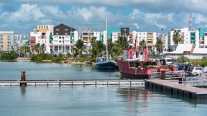 Un port de plaisance situé au bord de l’eau, avec des bateaux amarrés, une jetée et des bâtiments aux couleurs vives en arrière-plan.
