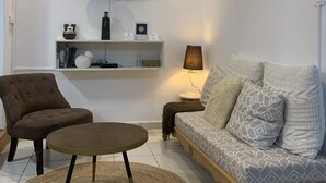 Un salon moderne comprenant un canapé, un fauteuil, une table basse et un téléviseur à écran plat fixé au mur.