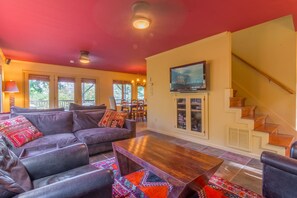 A living room with a sofa set, a coffee table, and a TV mounted on the wall.
