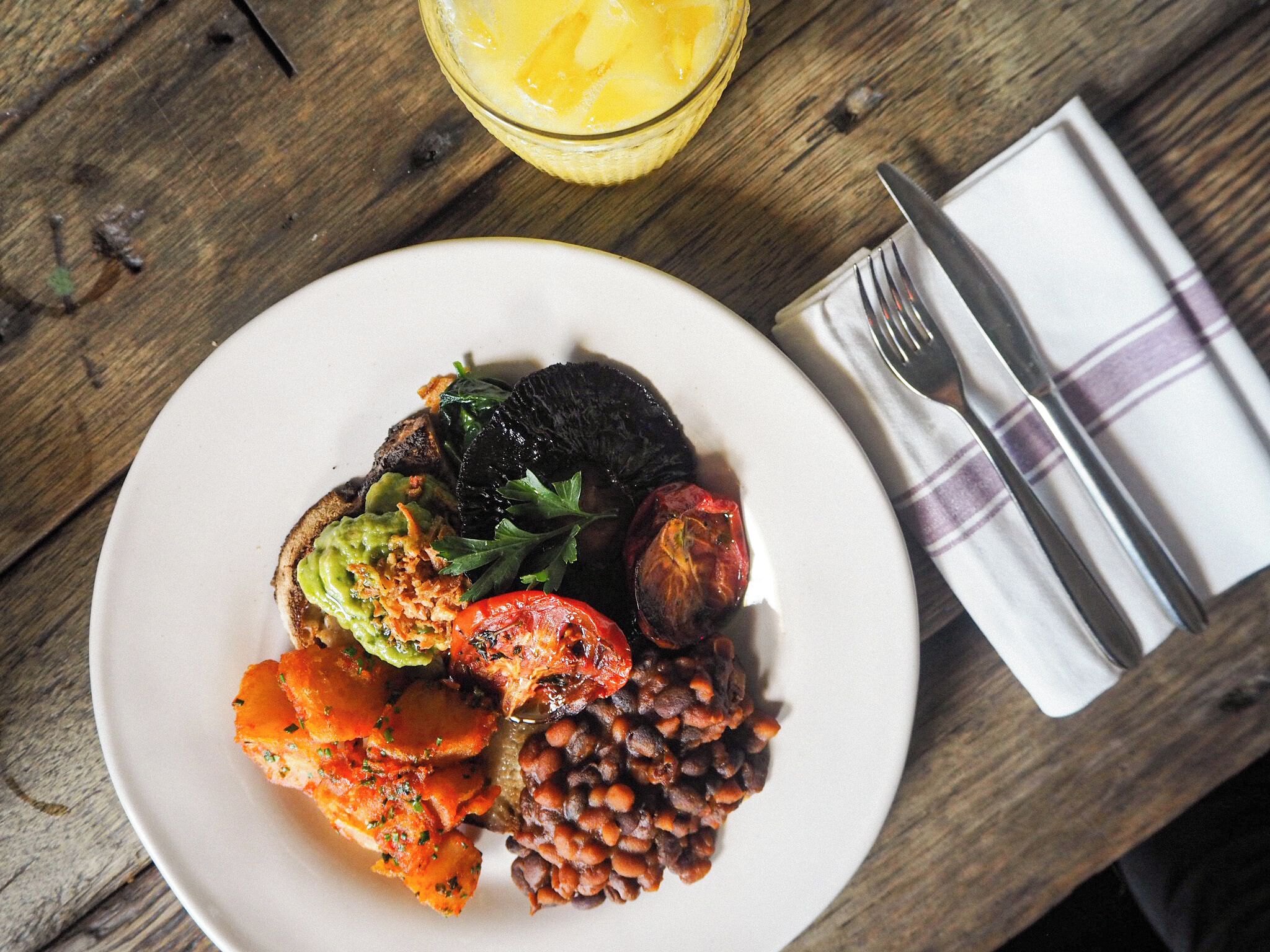 A plate of food with a glass of orange juice on a wooden table.