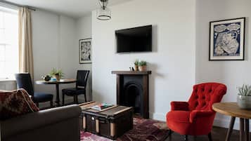 Ein Wohnzimmer mit Kamin, einem an der Wand befestigten Fernseher und einem roten Sessel.