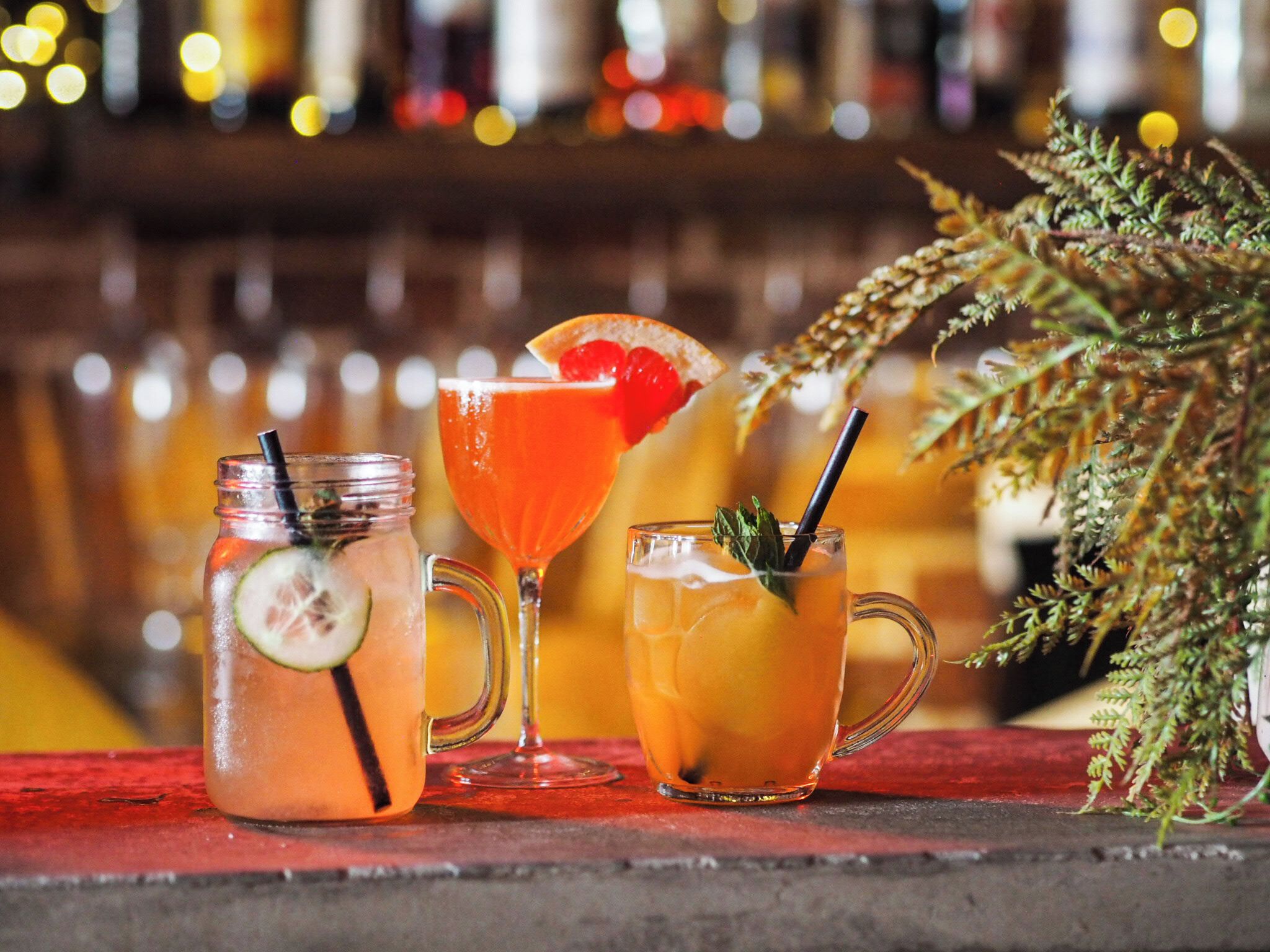 Tres bebidas sobre una barra, con un fondo difuso de luces.