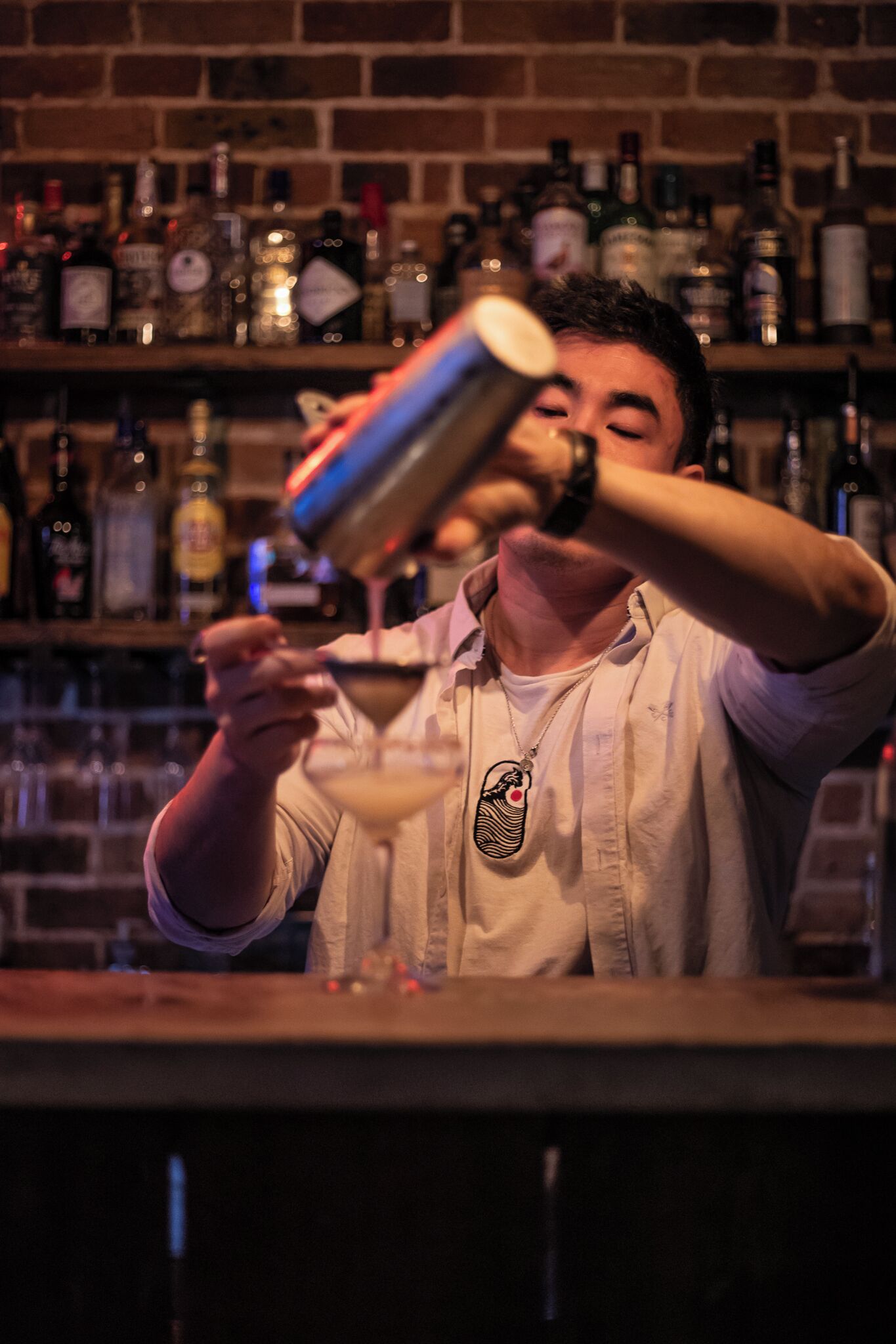 A bartender pouring a drink into a martini glass.