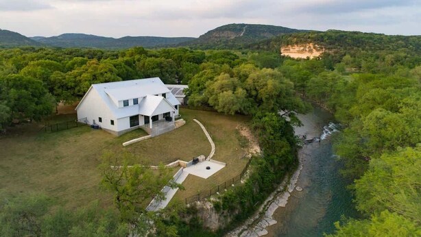 Een wit huis met een grote tuin en een rivier.