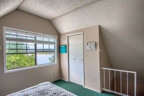 Une chambre à coucher avec un lit, une fenêtre avec des stores, une porte et un berceau.
