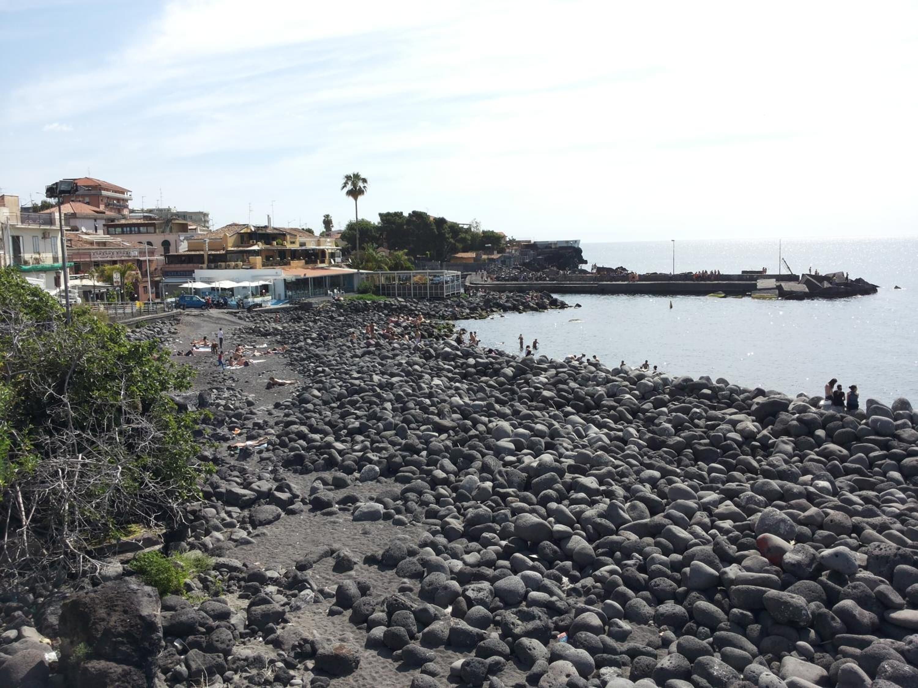 A rocky beach with buildings in the background.