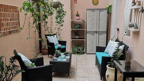 Un patio acogedor con mobiliario de mimbre, plantas en macetas y adornos colgantes.