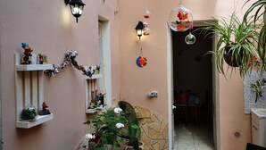 Un patio interior acogedor con lámparas colgantes, plantas en macetas y una mesa pequeña.