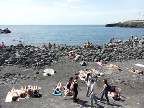 A beach with people sunbathing and swimming.