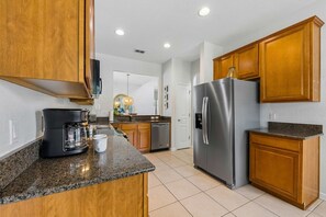 A modern kitchen with wooden cabinets, a stainless steel refrigerator, and a coffee maker on the counter.