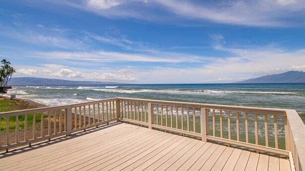 A wooden deck with a railing overlooking a beach with waves and distant mountains. - Oceanfront 2bd, lanai with Kaanapali pool views (Lahaina)