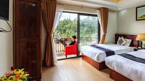 Ein Hotelzimmer mit zwei Betten, einem Balkon und Blick auf Grünflächen.