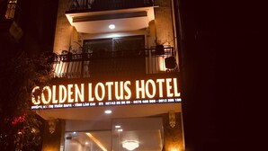 Das äußere Erscheinungsbild des Golden Lotus Hotels mit beleuchteter Beschilderung und mehreren Balkonen.