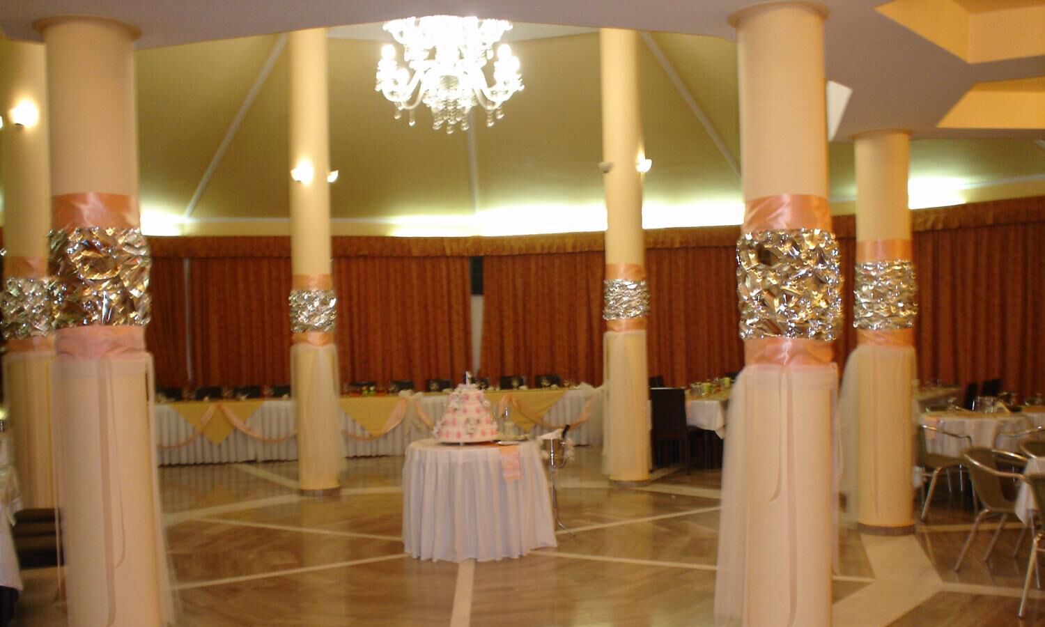 Una sala da banchetto con soffitti alti, lampadari e tavoli imbanditi per un evento formale.