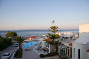 Relax by the rooftop pool surrounded by lounge chairs and umbrellas, overlooking the sea.