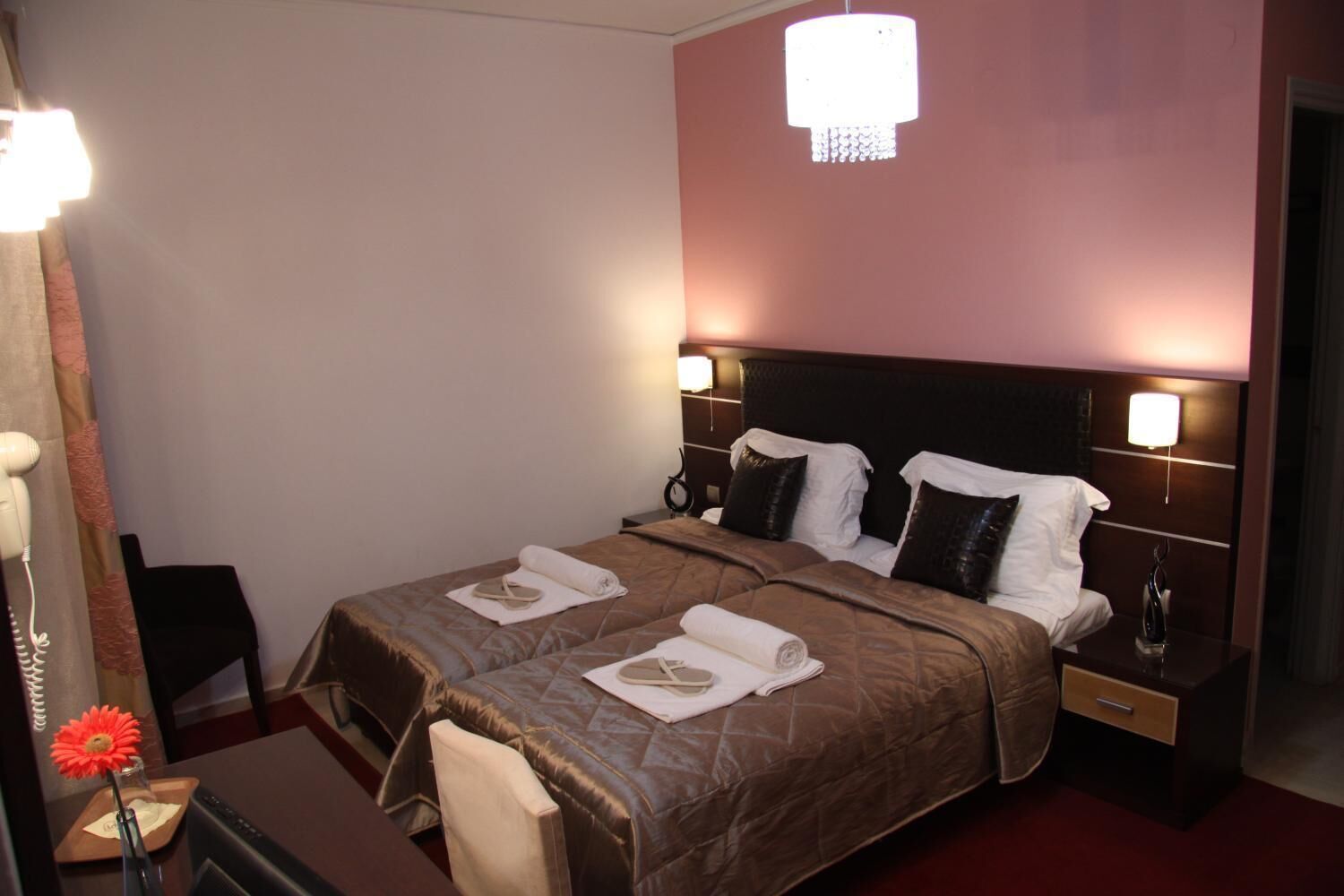A hotel room with a double bed, two bedside tables, a desk with a chair, and a mirror.