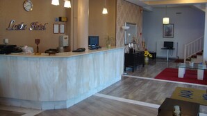 A hotel reception area with a marble counter, a clock, and a reception desk. - Lasia Hotel (Lesvos)