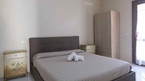 A bedroom with a bed, a wardrobe, and a nightstand. - Aria di Vacanza - Zenzero (Olbia)