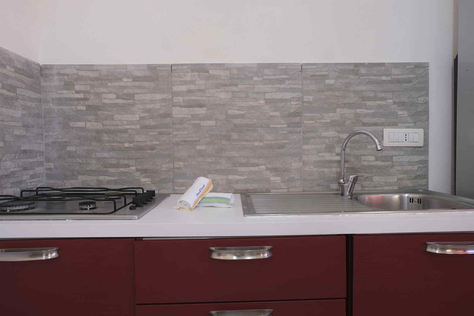 A kitchen with a gas stove, a sink, and a tiled backsplash.