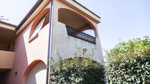 A building with a balcony, arched windows, and a tiled roof. - Aria di Vacanza - Zenzero (Olbia)