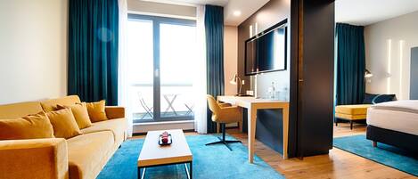 Une chambre d’hôtel équipée d’un canapé, d’un bureau, d’un lit, d’une télévision et offrant une vue sur l’extérieur.