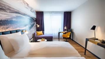 Ein Hotelzimmer mit einem großen Bett, einem Schreibtisch, einem Stuhl und Blick ins Freie.