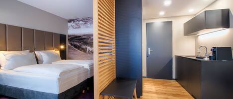 A modern bedroom with a bed, a desk, and a bathroom.