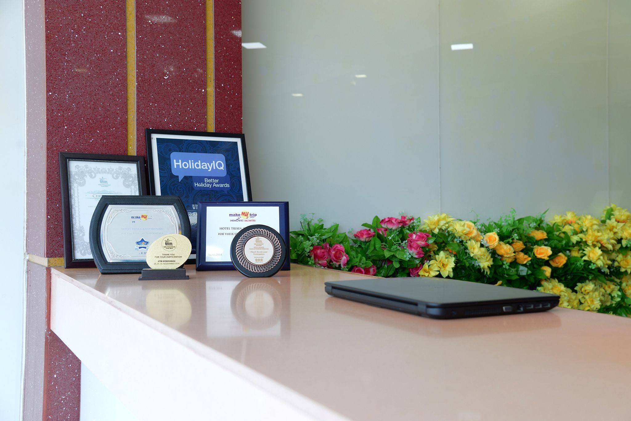 A reception desk with framed awards, a tablet, and a floral arrangement.