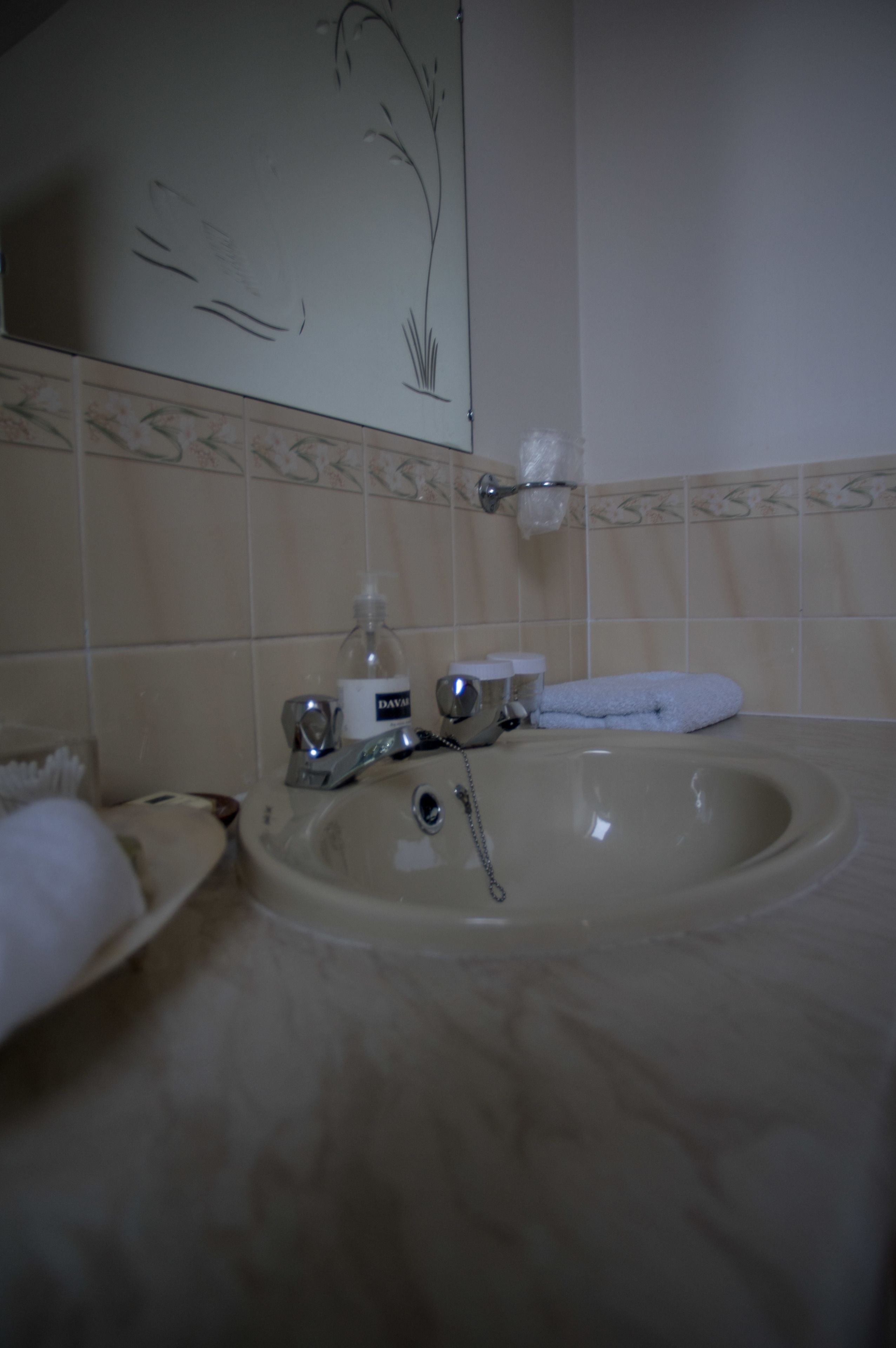 A bathroom with a sink, mirror, towel, and toiletries.