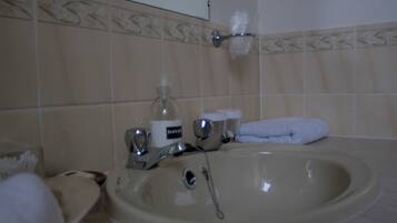 A bathroom with a sink, mirror, towel, and toiletries.