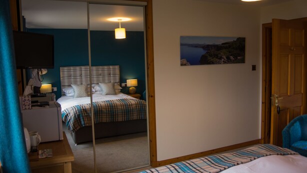 A bedroom with a bed, bedside tables, a mirror, and a painting on the wall.