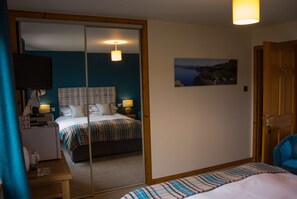 Un dormitorio con una cama, mesitas de noche, un espejo y un cuadro en la pared.