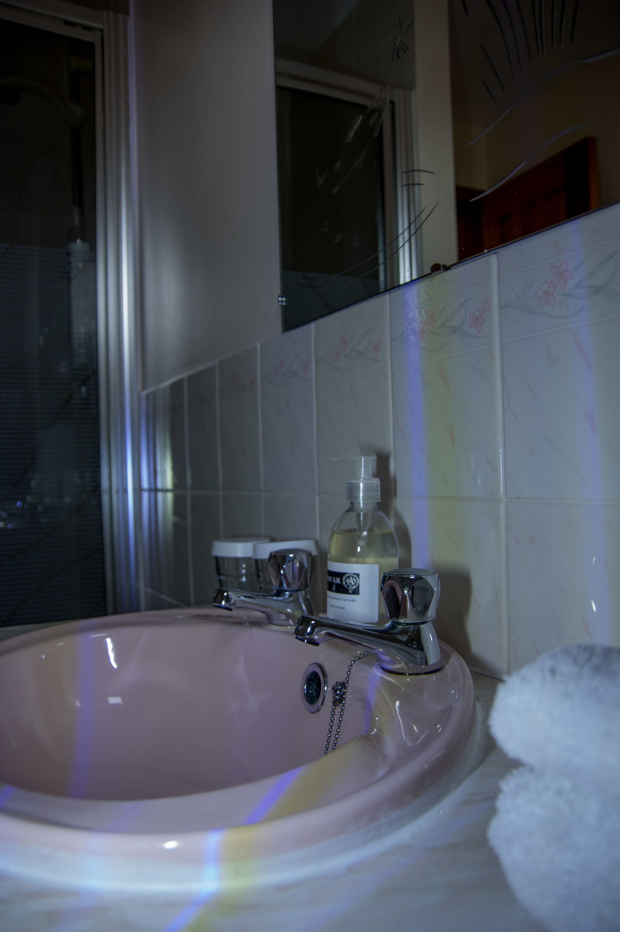 Ein Badezimmer mit einem rosa Waschbecken, einer Handseife und einem Handtuch.