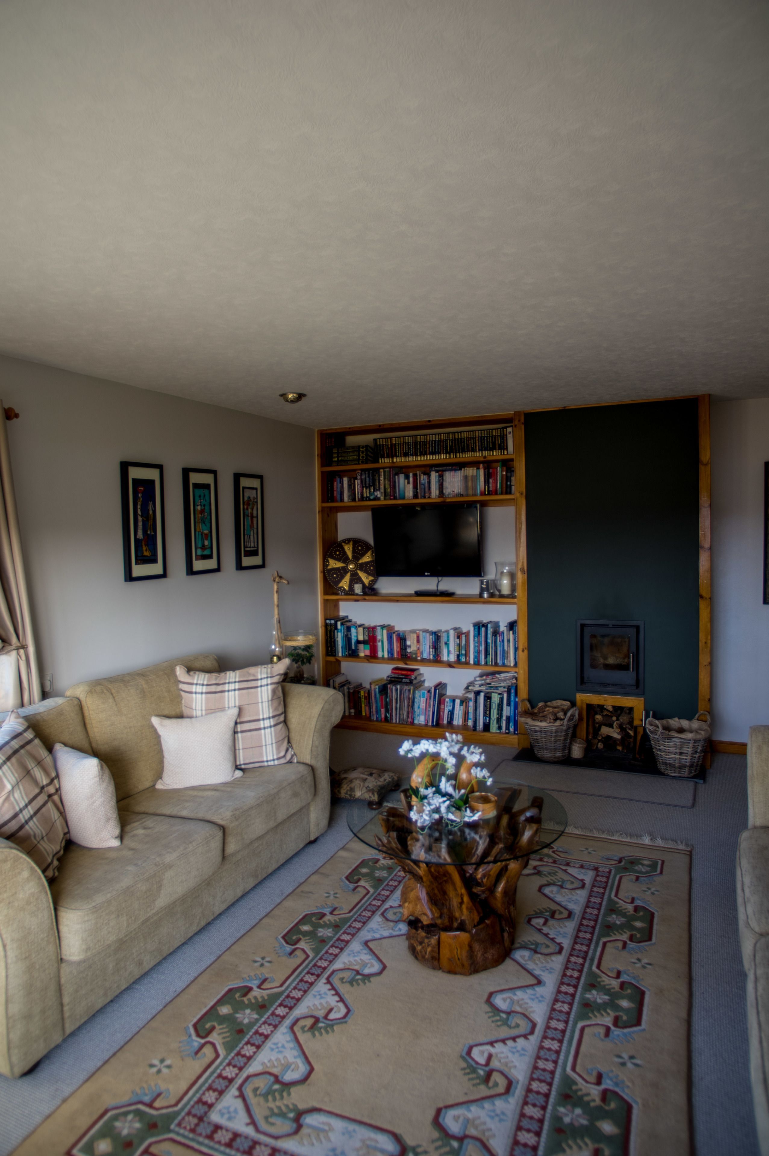 A cozy living room with a sofa, a coffee table with a decorative centerpiece, a bookshelf, and a television.