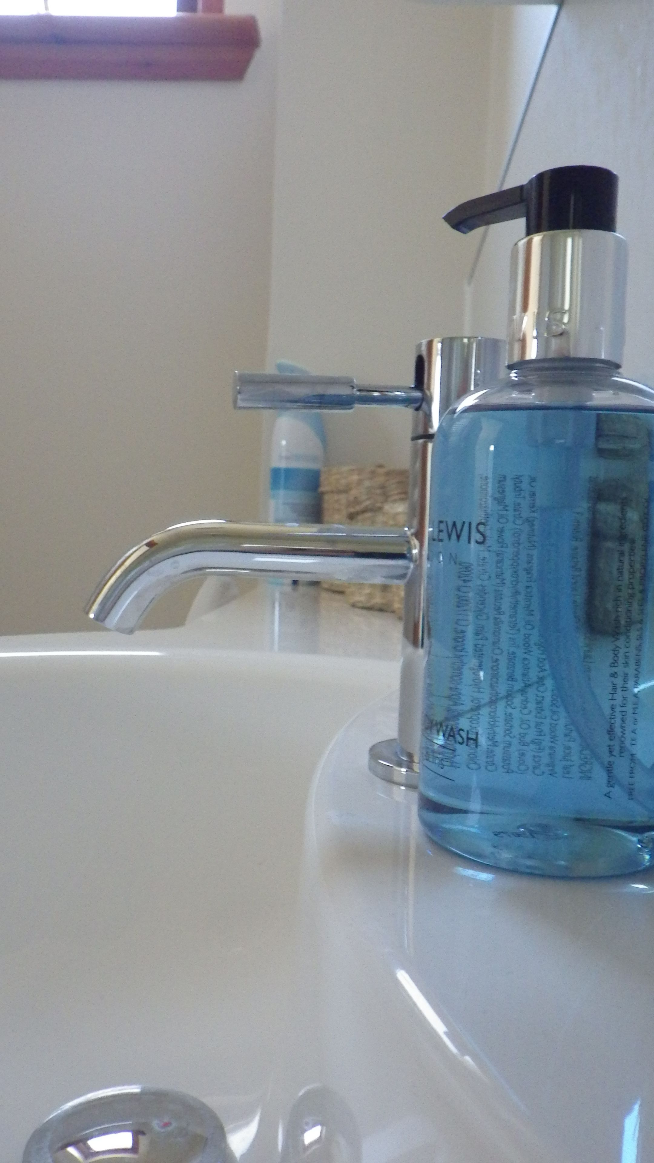 Un lavamanos con una botella azul de jabón líquido etiquetada 'LEWIS'.