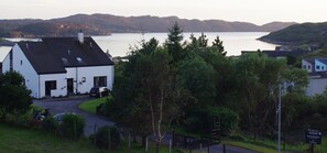 A white building with a black roof, a paved driveway, and a sign indicating 'Davar Bed & Breakfast' with no vacancies.