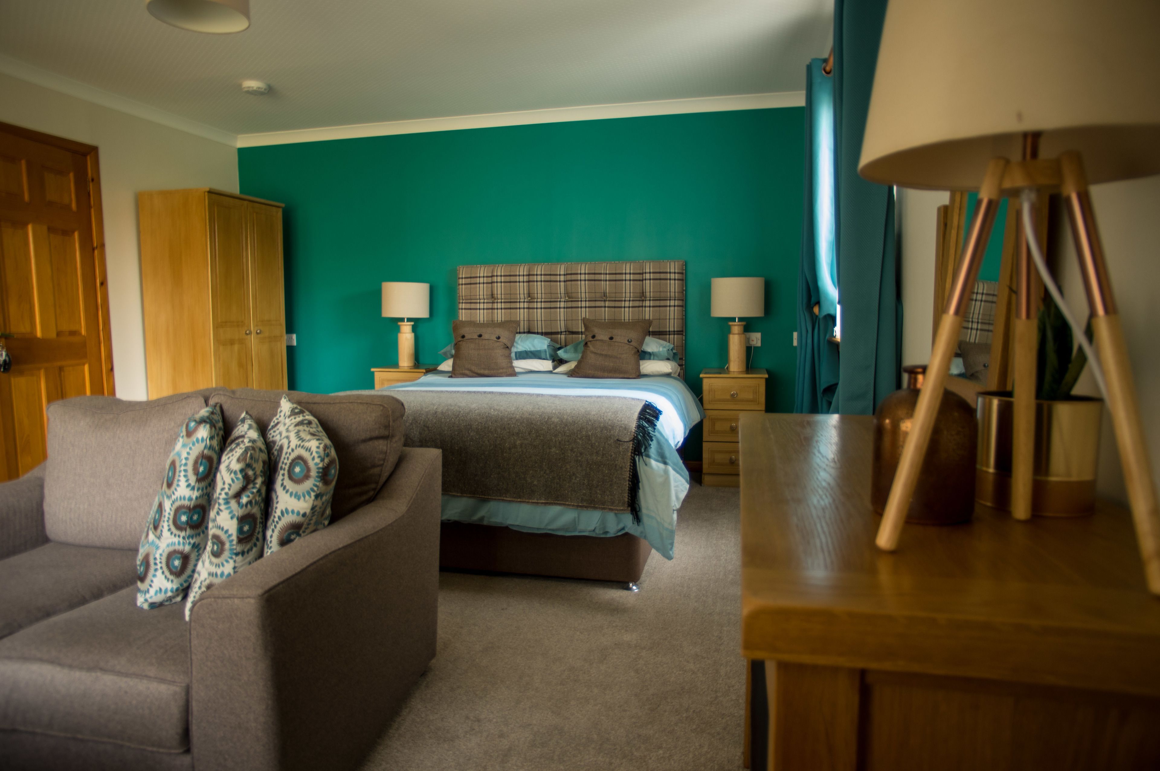 A bedroom with a bed, two bedside tables, a lamp, a wardrobe, and a sofa.