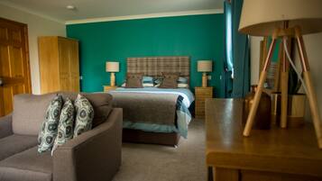 A bedroom with a bed, two bedside tables, a lamp, a wardrobe, and a sofa.