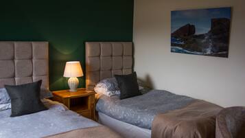 Una habitación de hotel con dos camas, una mesita de noche con lámpara y un cuadro en la pared.