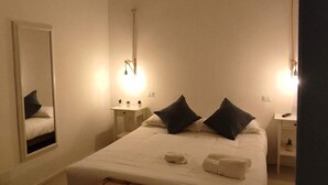 A hotel room with a large bed, bedside tables, a mirror, and a suitcase. - Sedilequattro Bed&Breakfast (Castellaneta)