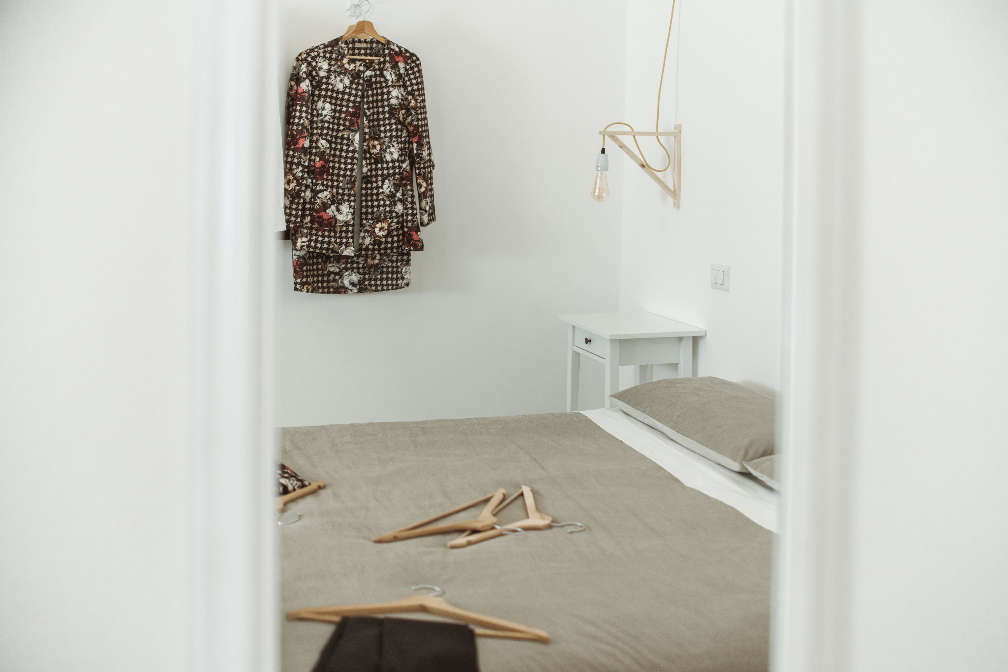 Ein Schlafzimmer mit einem Bett, einem Kleiderhaken und einem Nachttisch.