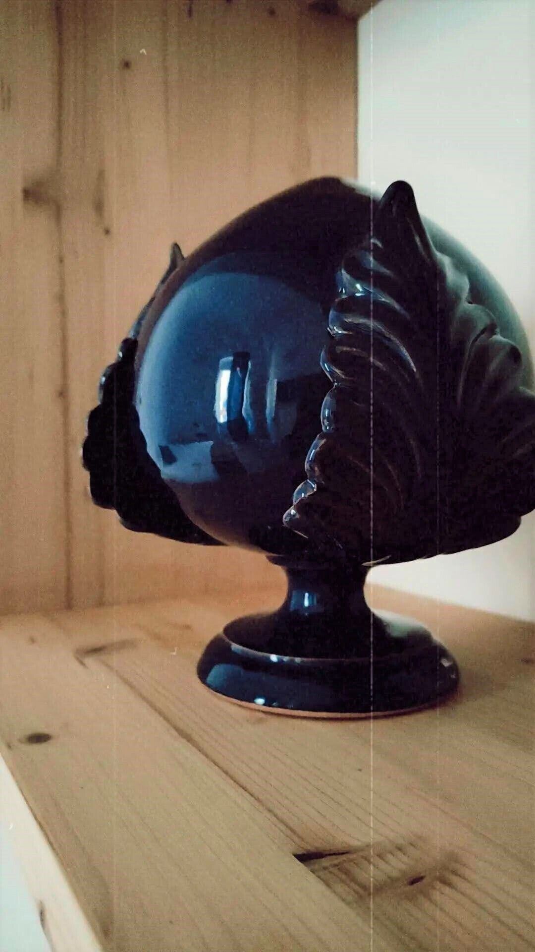 A black decorative object resembling a fish on a wooden surface.