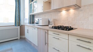 A modern kitchen with white cabinets, a microwave, a coffee maker, and a gas stove. - Clos 1 (De Panne)