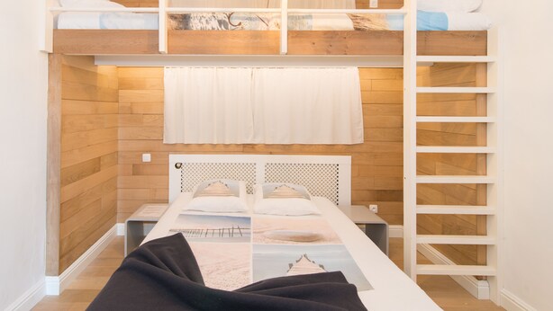 A bunk bed room with a wooden wall, a white headboard, and a ladder. - Clos 1 (De Panne)