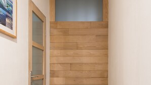 A narrow hallway with a wooden wall and a glass door on the left. - Clos 1 (De Panne)