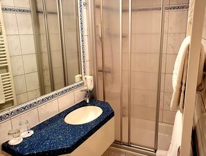 A bathroom with a blue speckled sink, a mirror, and a shower enclosure. - Baumhove Hotel Restaurant Am Markt (Werne)