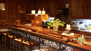 A bar area with wooden bar stools, a counter with a cash register, and a clock on the wall. - Baumhove Hotel Restaurant Am Markt (Werne)